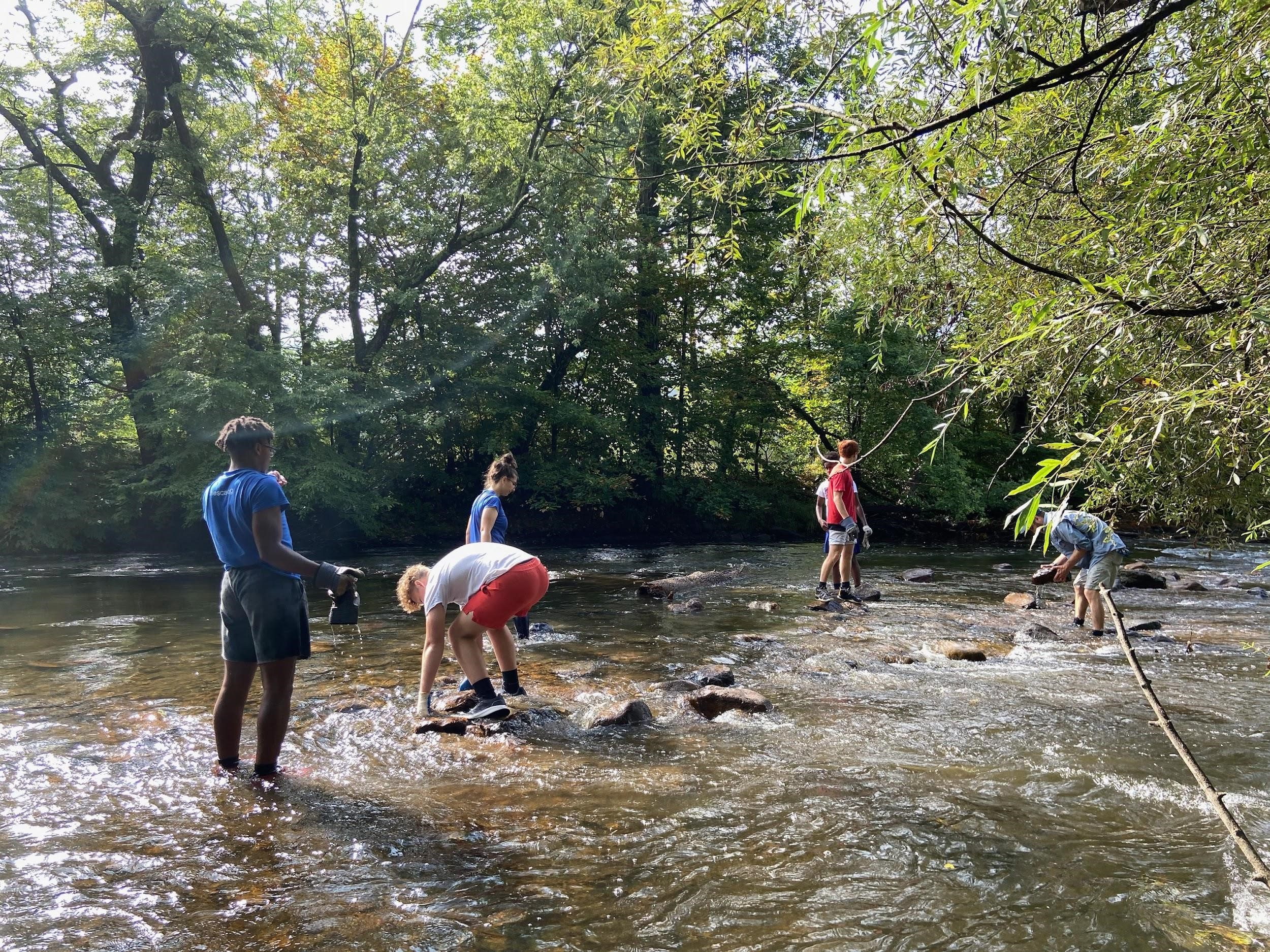 A group of people stand in a shallow river